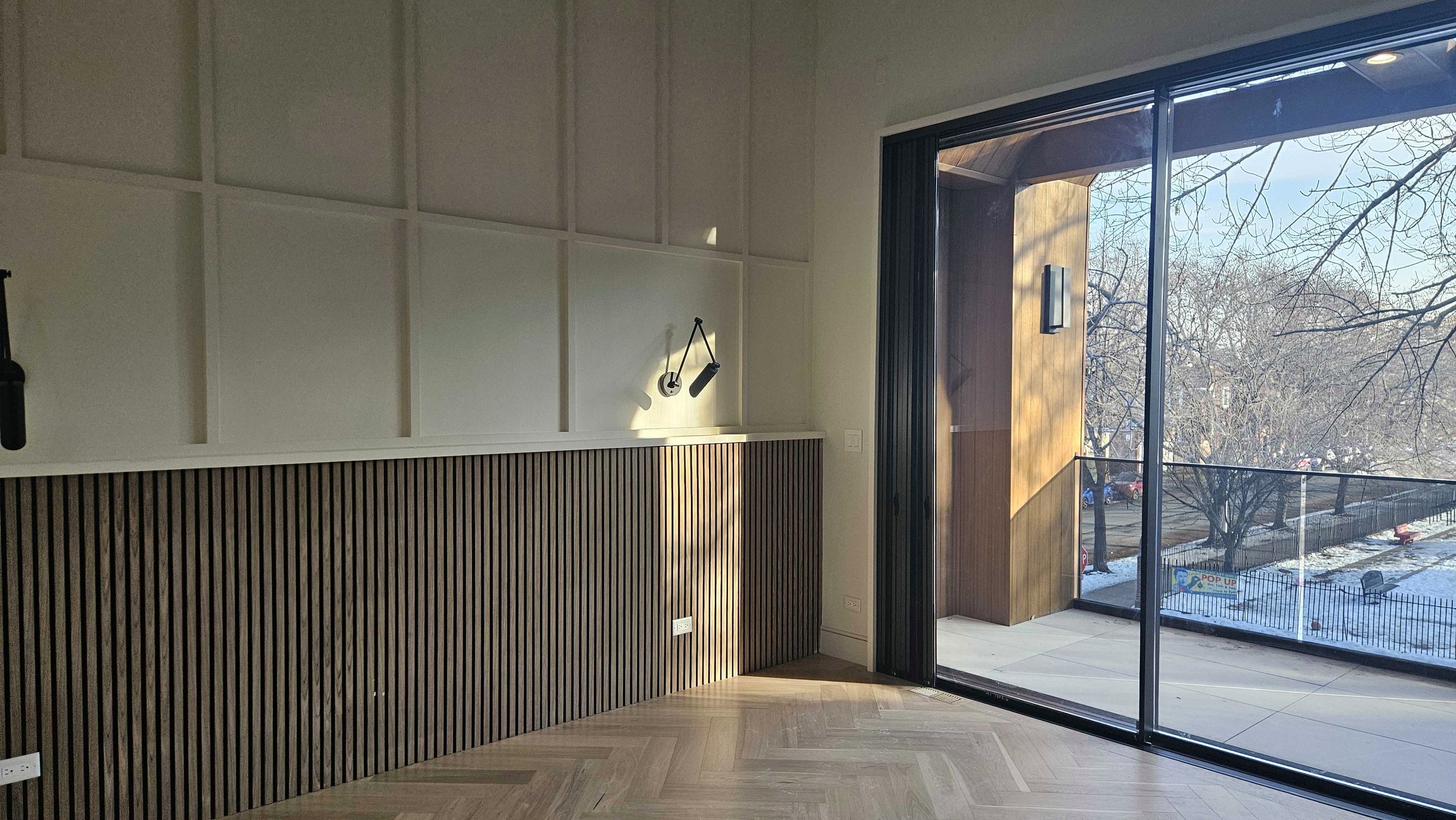 Bedroom with fluted wall panel, herringbone floor and floor-to-ceiling slider