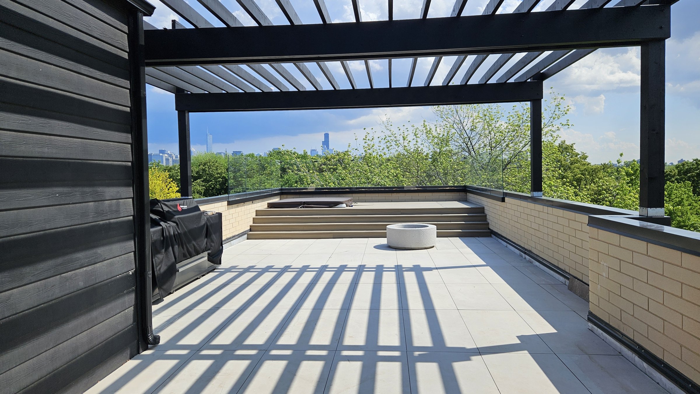 Black pergola over porcelain pavers, skyline view